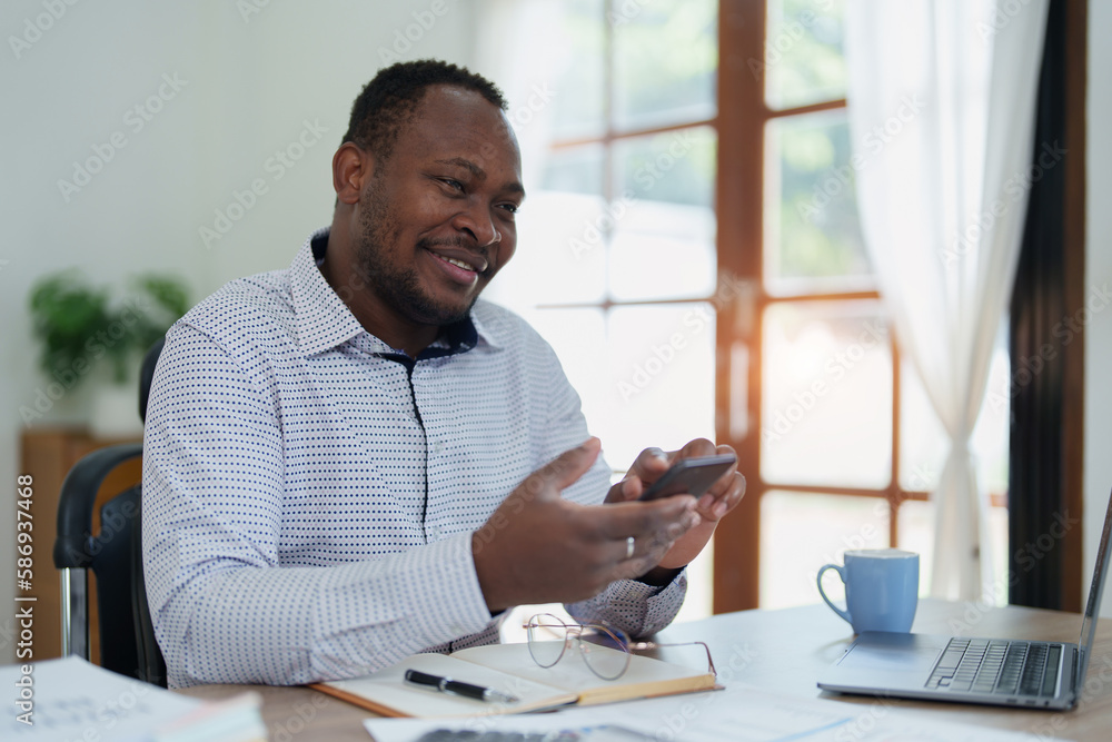 middle aged man American African using smart phone mobile and laptop computer with planning working on financial document, tax, exchange, accounting and Financial advisor middle aged man American African using smart phone mobile and laptop computer with planning working on financial document, tax, exchange, accounting and Financial advisor