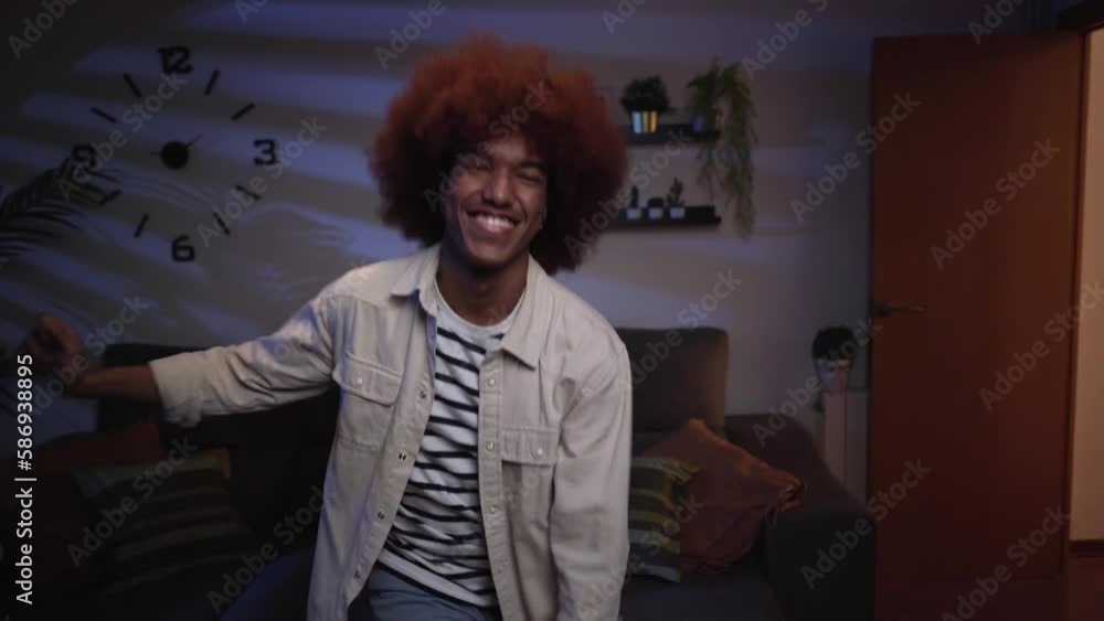 Charismatic and joyful afro-american young man dancing in the living room, having fun alone at home. Happy looking at camera. Charismatic and joyful afro-american young man dancing in the living room, having fun alone at home. Happy looking at camera.