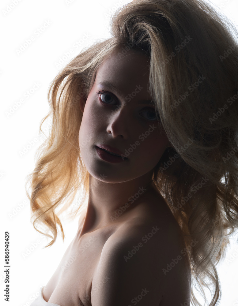 Beauty and make-up concept. Beautiful sexy woman with big wavy hair and pink make-up studio portrait in bright background. Model silhouette partly illuminated with light. Girl looking at camera Beauty and make-up concept. Beautiful sexy woman with big wavy hair and pink make-up studio portrait in bright background. Model silhouette partly illuminated with light. Girl looking at camera