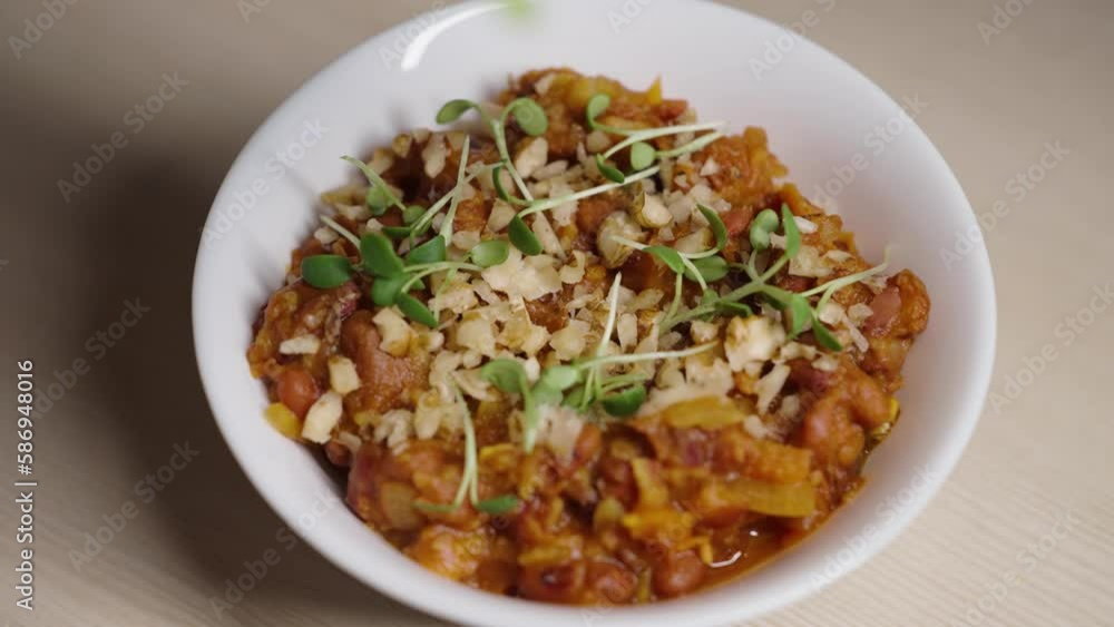 Chef adds microgreens to a dish of beans with walnuts close-up Chef adds microgreens to a dish of beans with walnuts close-up