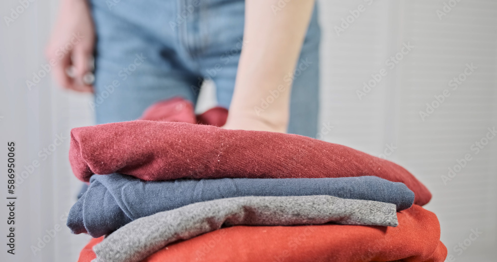 Women's hands press folded pile of clothes. Close-up, indoors. Concept of finishing homework, washing, ironing, a job well done. Women's hands press folded pile of clothes. Close-up, indoors. Concept of finishing homework, washing, ironing, a job well done.
