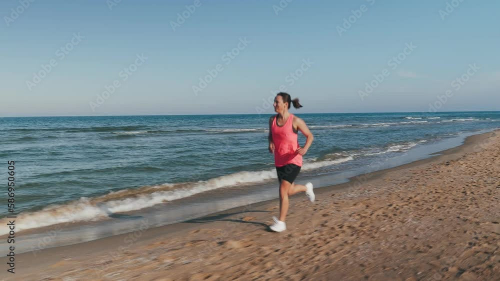 Running on beach. Happy smiling young woman jogging along seashore at sunset Running on beach. Happy smiling young woman jogging along seashore at sunset