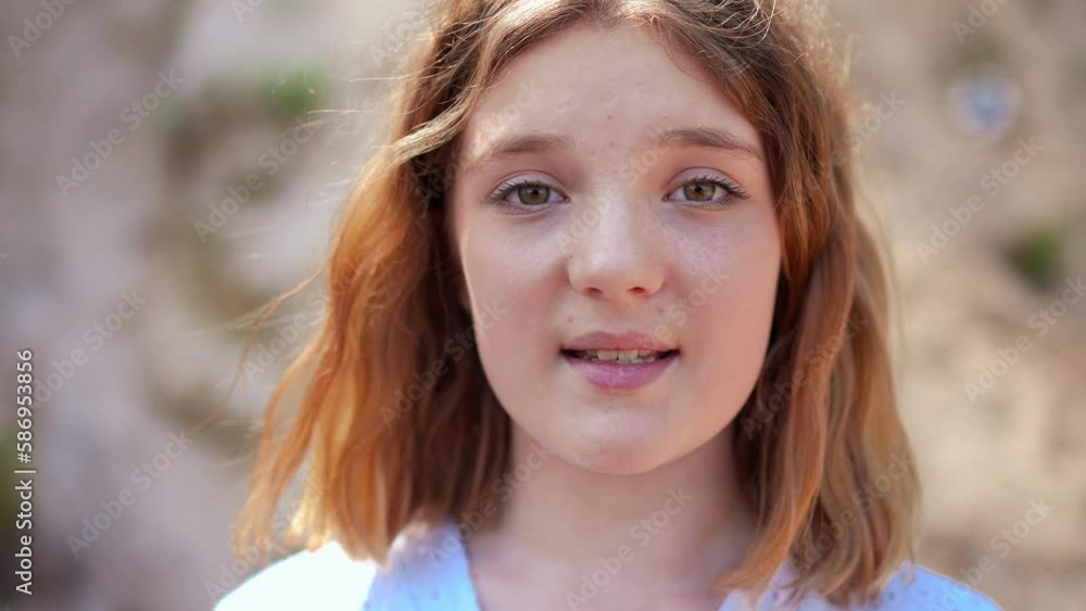 Front view headshot of confident girl singing looking at camera standing outdoors. Close-up face of talented inspired Caucasian singer posing performing on sunny day Front view headshot of confident girl singing looking at camera standing outdoors. Close-up face of talented inspired Caucasian singer posing performing on sunny day
