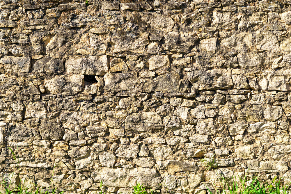 old grey stone wall textured with rough stone and sand cement filler