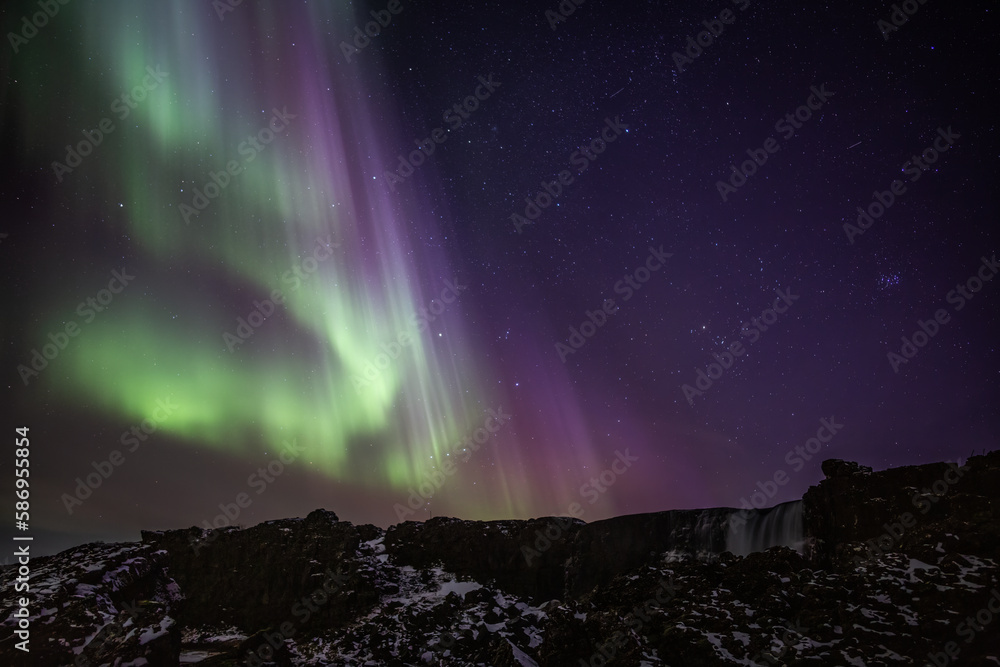 Bright aurora borealis and stars, Oxararfoss waterfall, Thingvellir Iceland