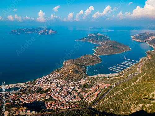 Aerial photo of Kaş Marina and Meis Island (Kastellorizo) in Antalya, Turkey, displaying yachts, turquoise waters, and cityscape. The area is popular among tourists for diverse activities.