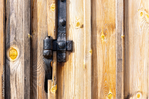 Old, black hinge fittings made by a blacksmith. Fittings installed on an old wooden door of an old shed