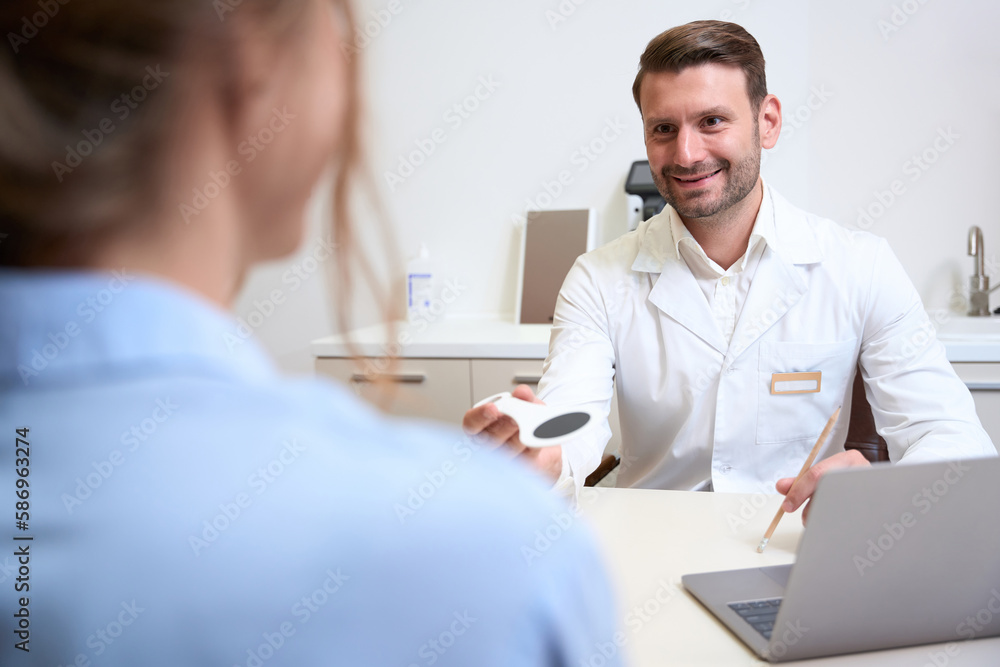 Fototapeta premium Handsome Caucasian ophthalmologist is getting consultation in his clinic