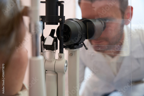 Ophthalmologist is looking throught the slit lamp in medical center