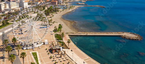 Fototapeta Naklejka Na Ścianę i Meble -  Aerial view of the Ferris wheel located on the waterfront of Civitavecchia in the Metropolitan City of Rome, Italy. On the city's waterfront there is a park, residential buildings and an empty beach.