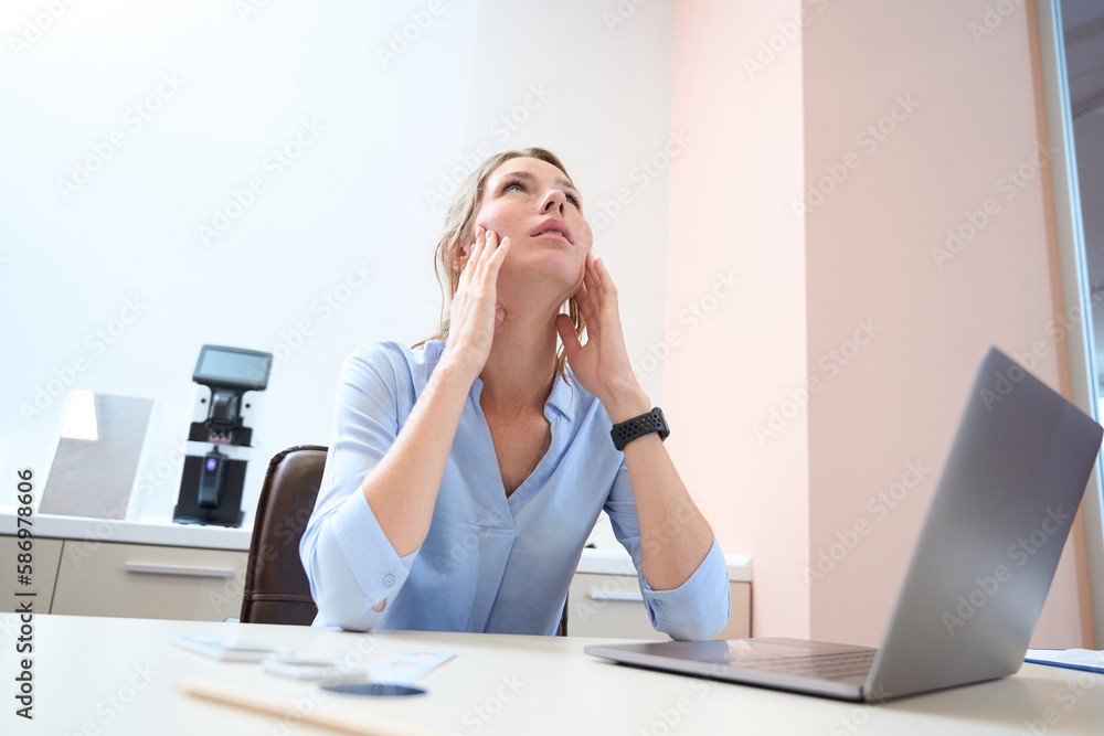 Caucasian female is thinking while holding her head by hands in the office Caucasian female is thinking while holding her head by hands in the office