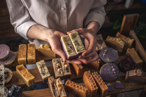 Female soap maker holds a handmade lavender soap in her hands. A lot of different sliced pieces. Eco-friendly natural craft cosmetics