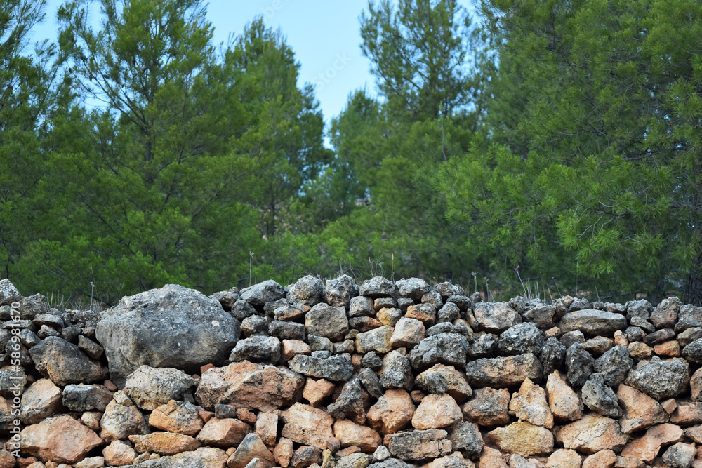Close up view of an old stone wall of stacked rocks in a forest or country place. Agricultural terrace