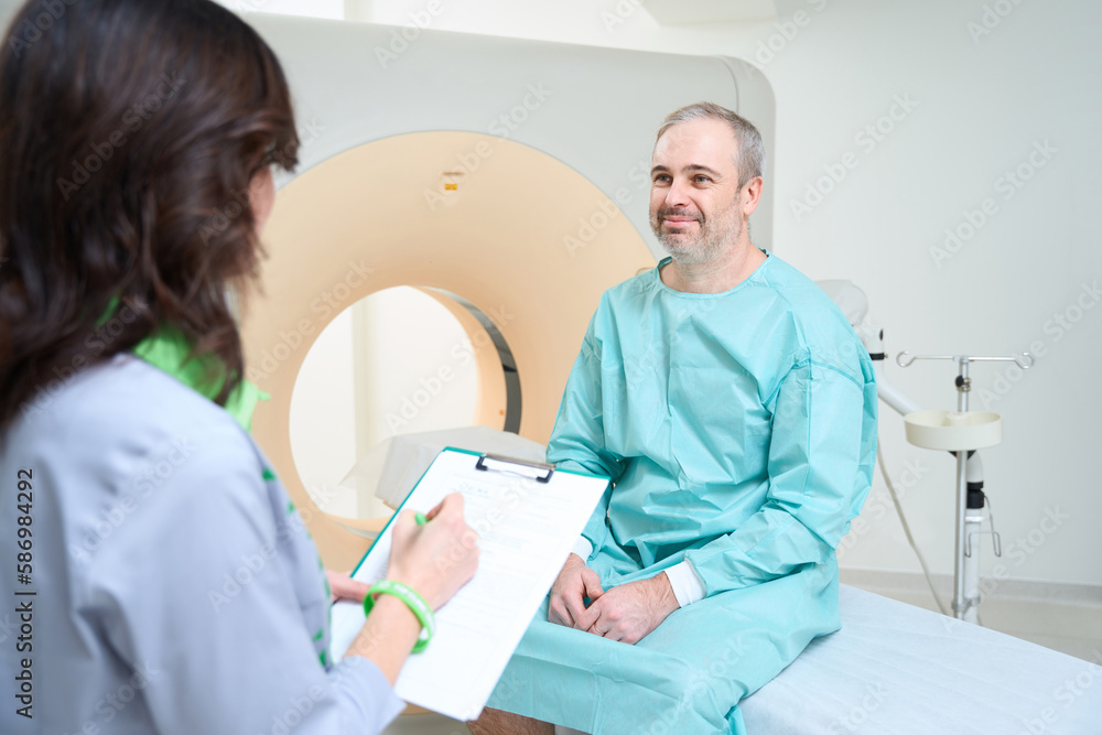 Obraz premium Doctor filling out a patient questionnaire before CT diagnostic procedure