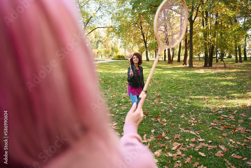 Fototapeta Naklejka Na Ścianę i Meble -  Smiling lady playing badminton with someone in park