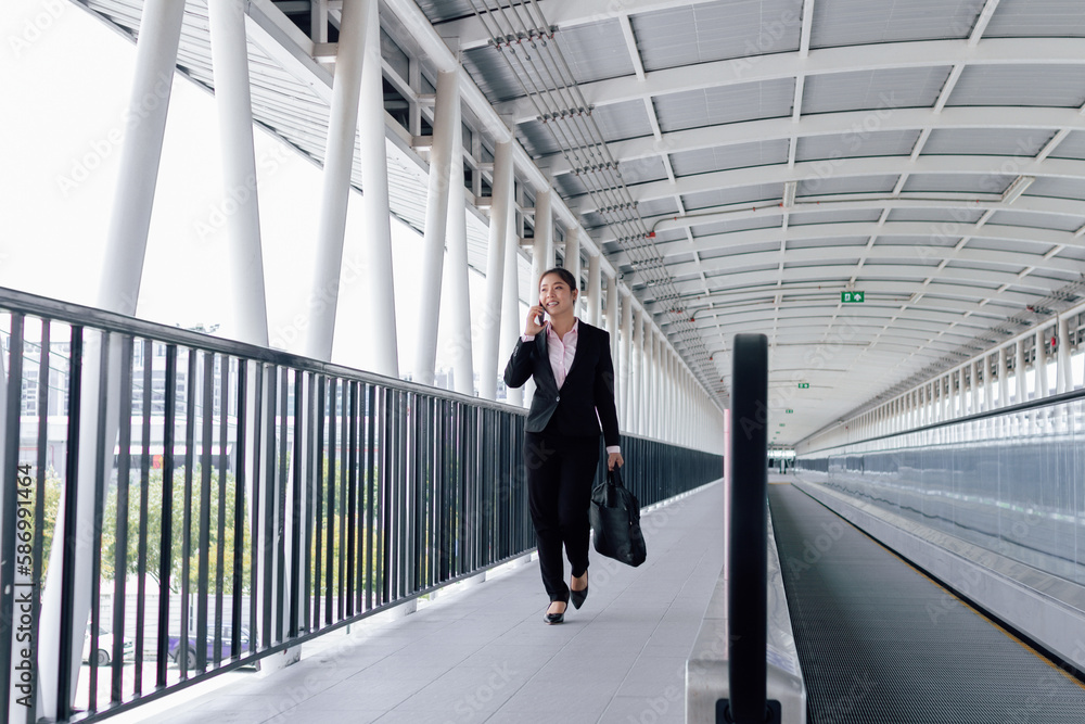 young Asian businesswoman in black suit using digital tablet and standing on walkway station with copy space. young Asian businesswoman in black suit using digital tablet and standing on walkway station with copy space.