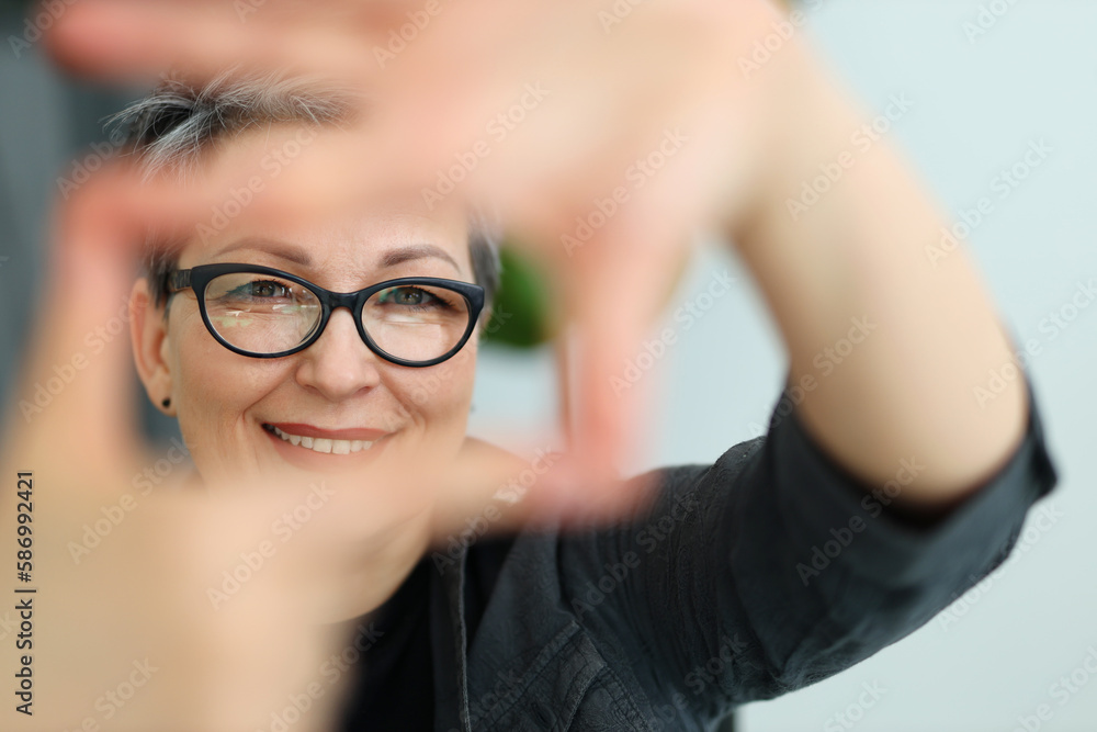 Portrait of a beautiful adult woman in glasses who makes a frame with her hands. Portrait of a beautiful adult woman in glasses who makes a frame with her hands.