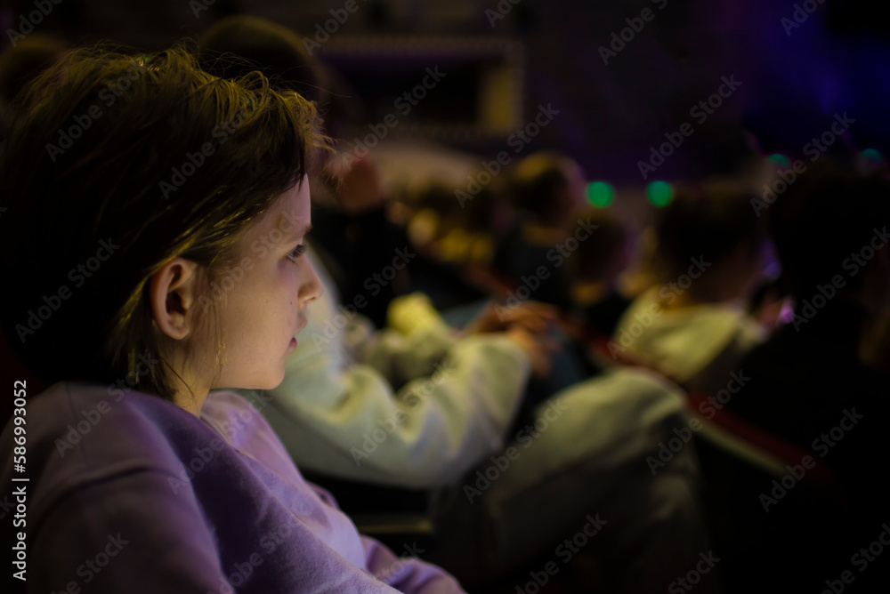a boy sits in a crowded cinema or theater hall, watches a performance, movie or concert a boy sits in a crowded cinema or theater hall, watches a performance, movie or concert