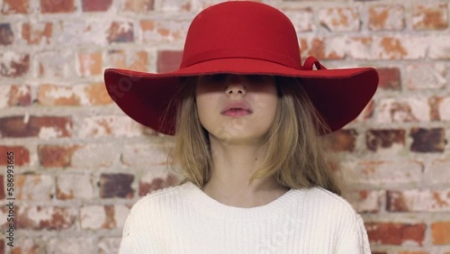 A sad girl in a red hat looks at the camera.