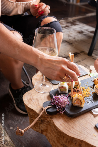 Mujeres y manos femeninas comiendo sushi en un restaurant con vajill rustica photo