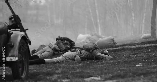 Re-enactor Dressed As Soviet Russian Soldier Lies Slain In Reconstruction Of Battles World War I Near Combat Sidecar. Soviet Russian Infantry Soldier In World War Ii. Black And White Video. photo