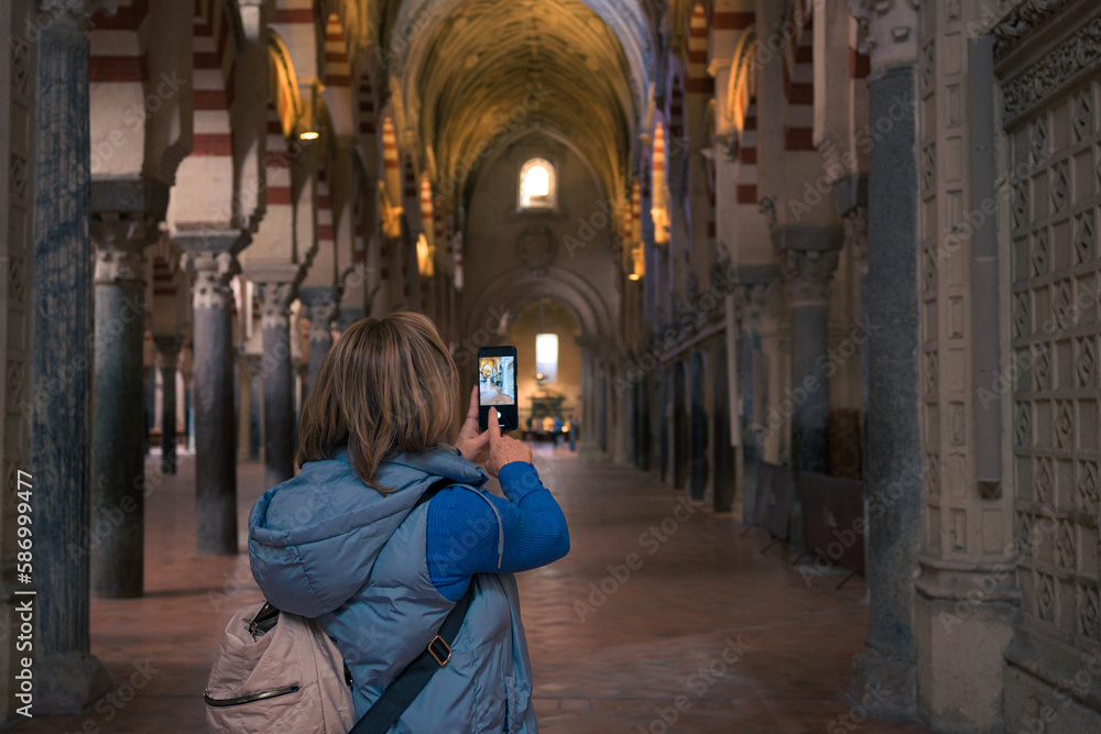 Middle-aged woman takes a photo with her mobile phone in the interior of a cathedral
