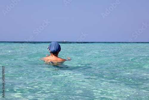 Woman in sun hat swimming in azure sea water. Beach vacation on Caribbean islands