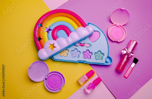 Children's set of decorative cosmetics for a little girl in the shape of a rainbow. Flat lay.