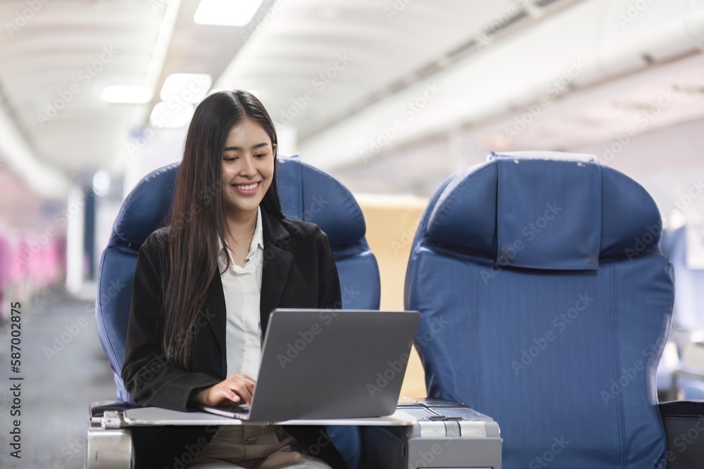 Asian young woman using laptop sitting near windows at first class on airplane during flight, Traveling and Business concept Asian young woman using laptop sitting near windows at first class on airplane during flight, Traveling and Business concept