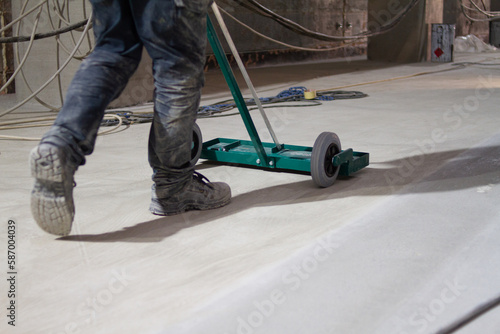 The worker is skillfully using a mechanical brush to clean and polish the surface of the floor, ensuring that it remains in top condition. © Doralin