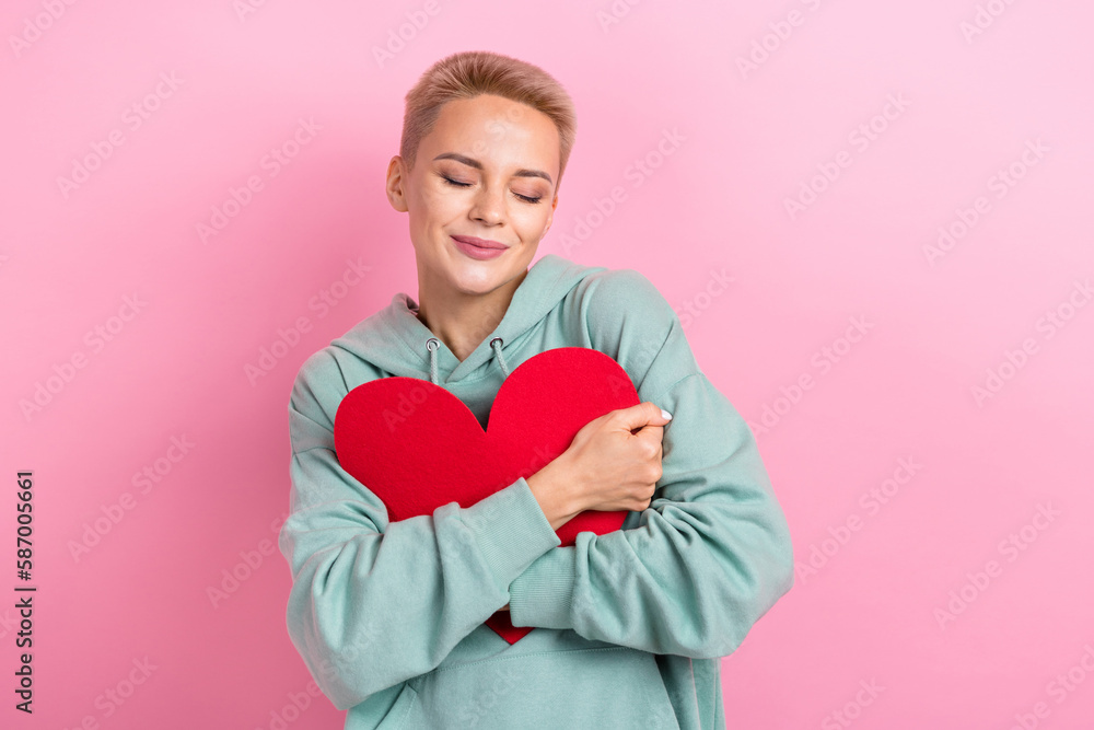 Photo portrait of lovely young lady embrace red heart card closed eyes cute wear trendy khaki garment isolated on pink color background Photo portrait of lovely young lady embrace red heart card closed eyes cute wear trendy khaki garment isolated on pink color background