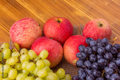 Different grapes and apples on a wooden background. Healthy food.