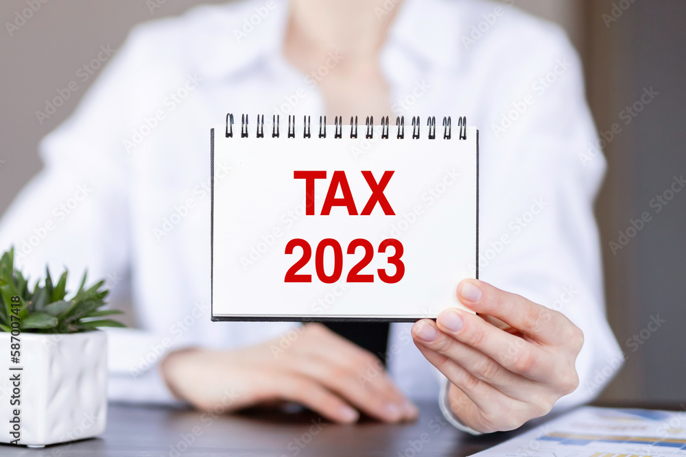 Text TAX 2023 on a notebook in the hands of a businesswoman. Text TAX 2023 on a notebook in the hands of a businesswoman.