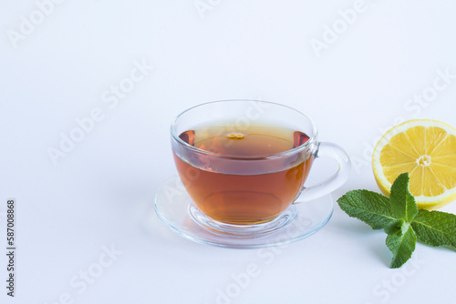 Black tea in the glass cup, lemon and mint on the white background. Copy space. Close-up.