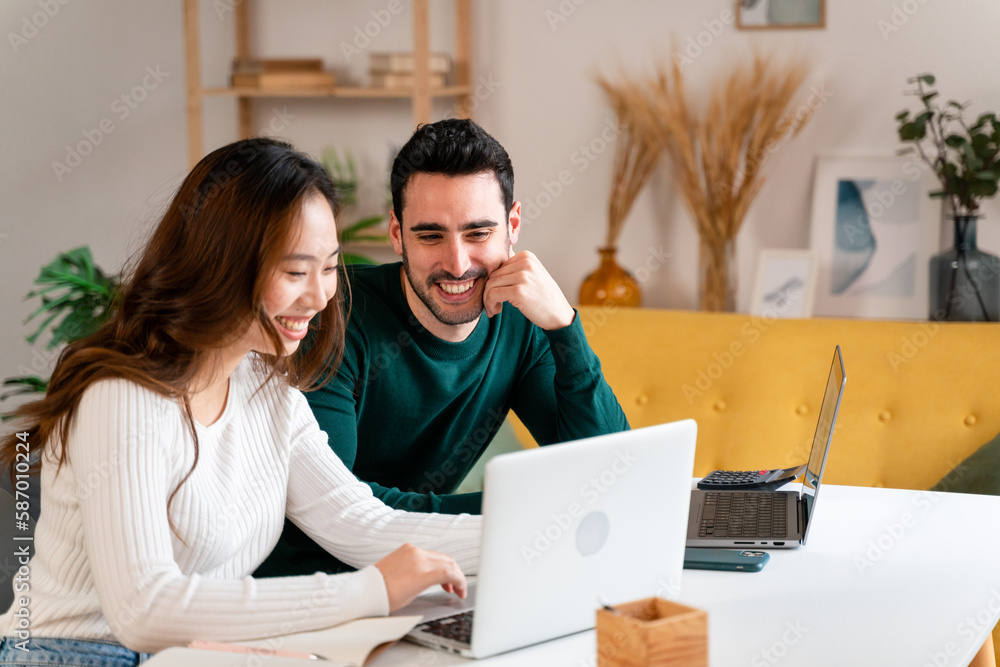 Happy couple working on laptop and making notes Happy couple working on laptop and making notes