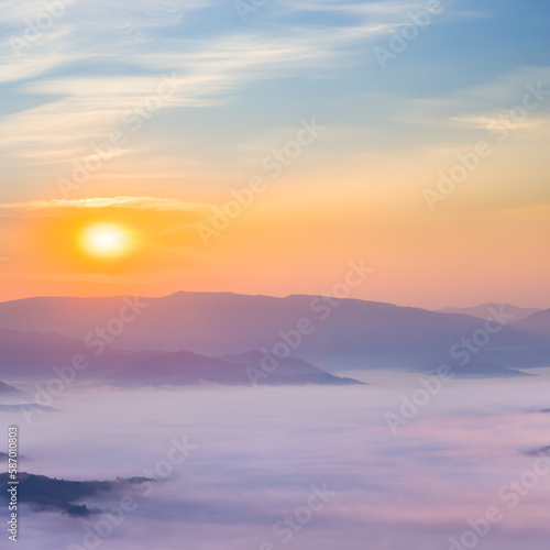 mountain valley in dense mist at the sunrise, early morning mountain landscape