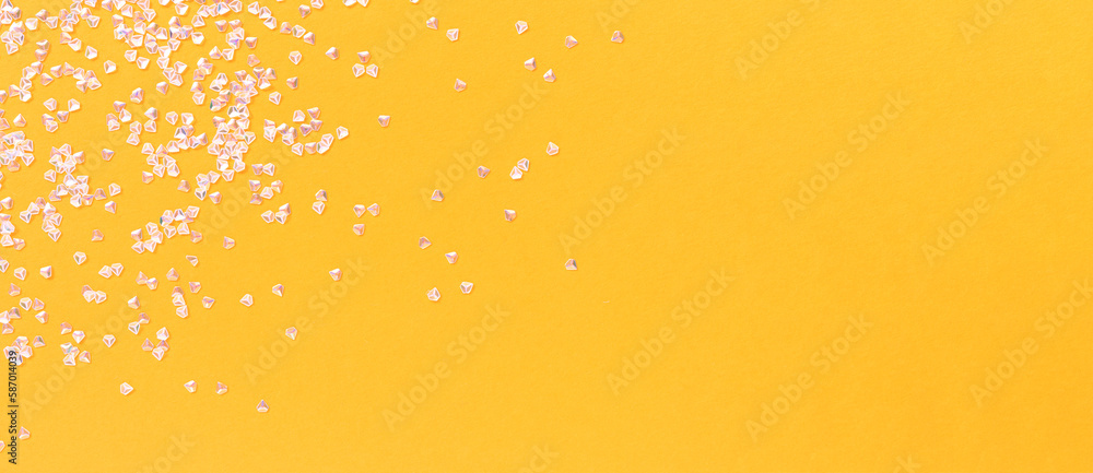 Glowing silver crystal confetti scattered on a yellow background. Festive concept with place for text.