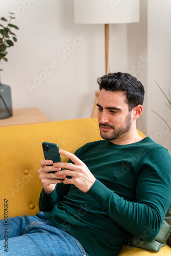 Young man using smartphone on sofa
