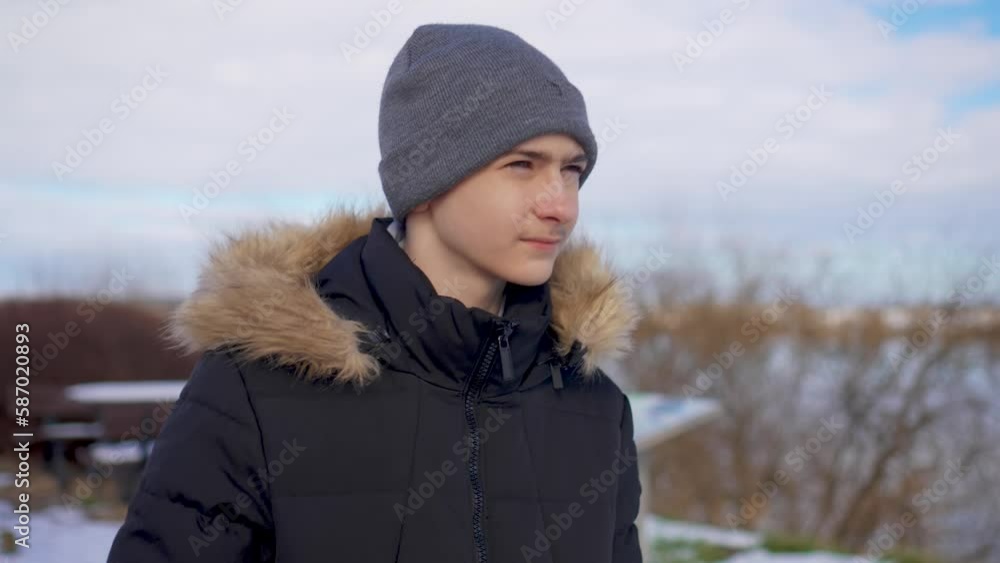 Portrait of handsome boy student walks along snowy road street on outskirts of city near river Vistula in Poland. Young people lifestyle concept Portrait of handsome boy student walks along snowy road street on outskirts of city near river Vistula in Poland. Young people lifestyle concept