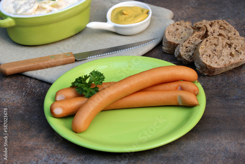 Wiener Würstchen auf einem Teller mit Kartoffelsalat und Senf.