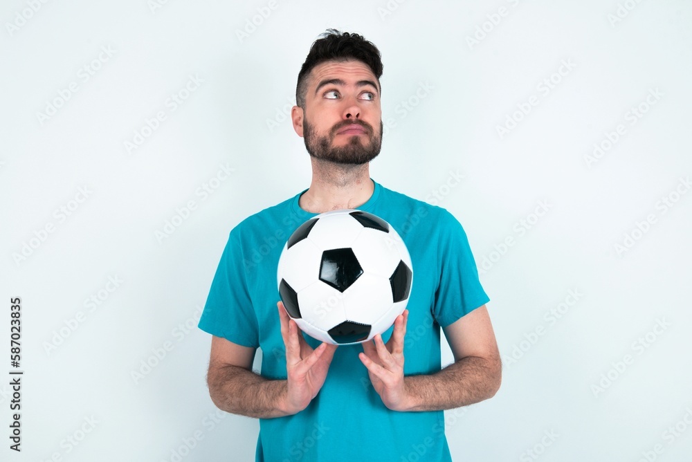 Charming cheerful Young man holding a ball over white background making up plan in mind holding hands together, setting up an idea.