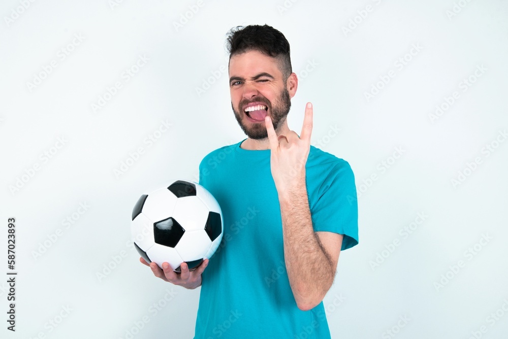 MYoung man holding a ball over white background ODEL making rock hand ...