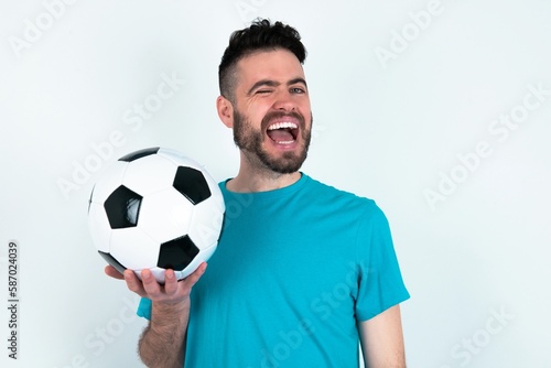 Young man holding a ball over white background winking looking at the camera with sexy expression, cheerful and happy face.