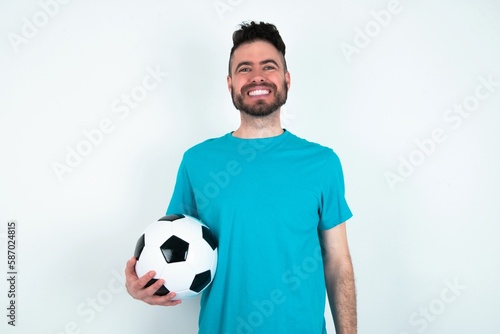 Young man holding a ball over white background with a happy and cool smile on face. Lucky person.