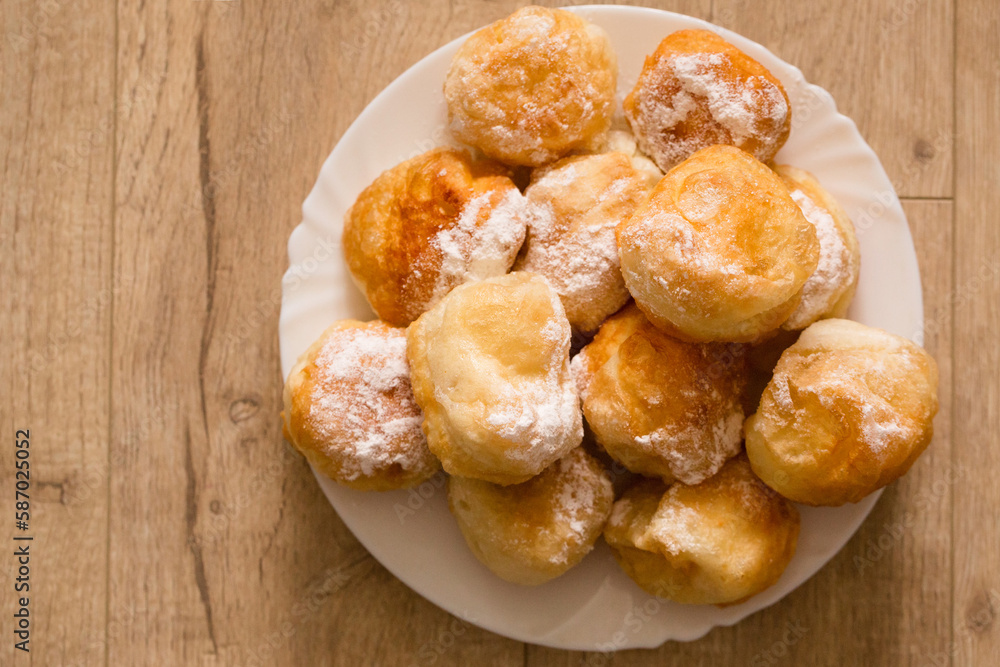 Ruddy fragrant donuts sprinkled with powdered sugar in a plate