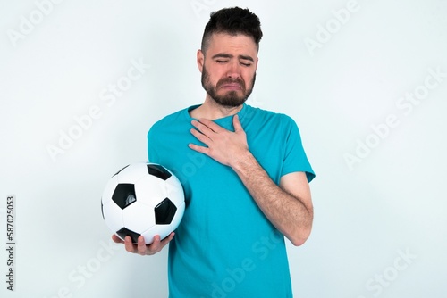 Sad Young man holding a ball over white background desperate and depressed with tears on her eyes suffering pain and depression in sadness facial expression and emotion concept