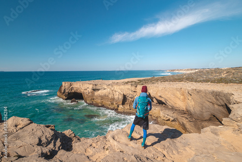 Passionate young backpacker tracks rocky cliffs on the Atlantic coast near Vila Nova de Milfontes  Odemira  Portugal. In the footsteps of Rota Vicentina. Fisherman trail