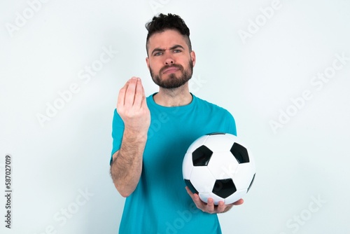 Young man holding a ball over white background Doing Italian gesture with hand and fingers confident expression