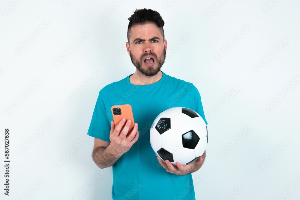 Photo of interested Young man holding a ball over white background hold telephone look side empty space screen