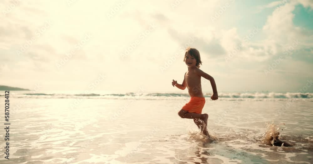 Kid have fun in family vacation on the sea. Boy running on the waves Kid have fun in family vacation on the sea. Boy running on the waves